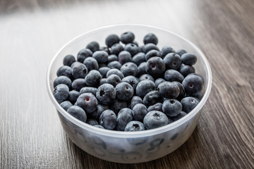 Ripe tasty blueberries and berries on a wooden table in a bowl