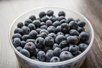 Ripe tasty blueberries and berries on a wooden table in a bowl