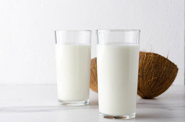 Two glasses of organic coconut milk kefir on white clean table against white 