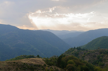 Sonnenstrahl bricht aus den Wolken über den Bergen