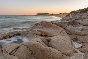 French landscape - Bretagne. A beautiful beach with rocks and fortress in the background at sunrise.