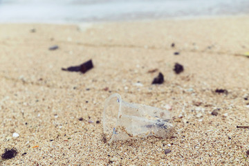 Plastic trash at the sandy beach. Plastic pollution concept. Single-use plastic is a human addiction that is destroying our planet and impacts our waters, sea life and humans.