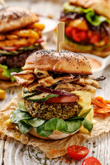 Vegan burger, green peas burger, homemade burger with green peas cutlet, grilled mushrooms, zucchini,  tomato, red onion, lamb's lettuce, and curry sauce on a wooden background. Healthy eating concept