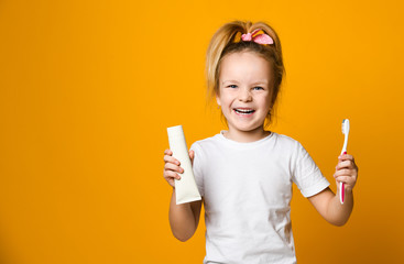 Beauty girl holding toothbrush and winking isolated over yellow background