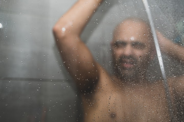 British Asian man taking a shower in the shower cubicle - with copy space. 