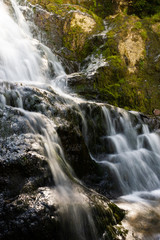 Scenic waterfall on mountain river in summer forest. Travel along river.