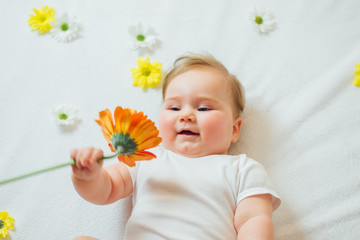 Beautiful baby holding a flower on white blanket