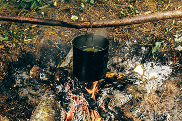 Tourist bowler on fire. Tourism, cooking in field conditions. Wild forest conditions for survival.