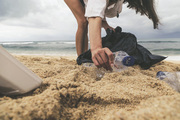 Volunteer woman collecting trash on the beach. Trash-free seas concept. Single-use plastic is a...