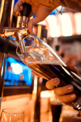 close-up of barman hand at beer tap pouring a draught lager beer