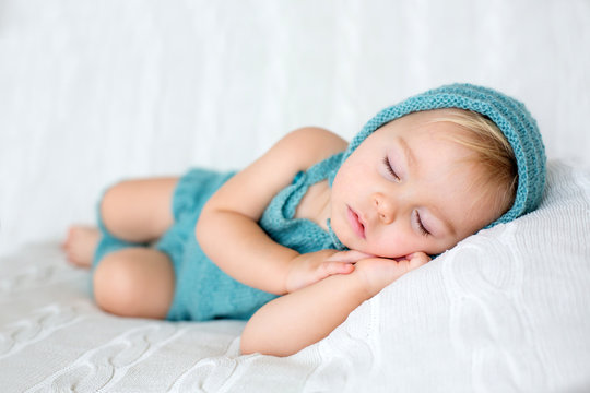Sweet toddler boy, sleeping with teddy bear toy, cute knitted outfit