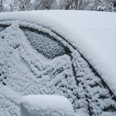 Car covered by snow in winter season. Side view in selective focus.