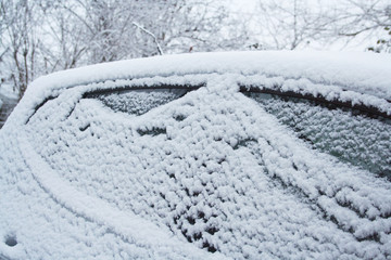 Car covered by snow in winter season. Side view in selective focus.