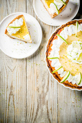 Homemade sweet cake, classic key lime pie with fresh limes, on wooden background copy space