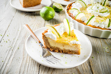 Homemade sweet cake, classic key lime pie with fresh limes, on wooden background copy space