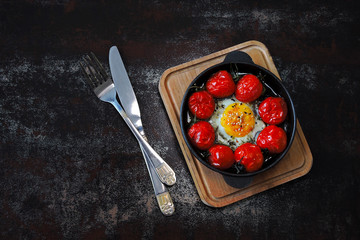 Baked egg with cherry tomatoes in a cast iron skillet. Healthy breakfast. Keto diet.