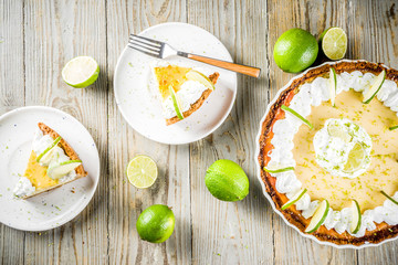 Homemade sweet cake, classic key lime pie with fresh limes, on wooden background copy space