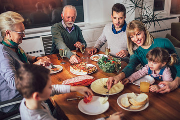 Multi generation family enjoying meal around table at home - Powered by Adobe