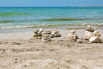 a pyramid of stones on a pebble beach against the sea and sky.