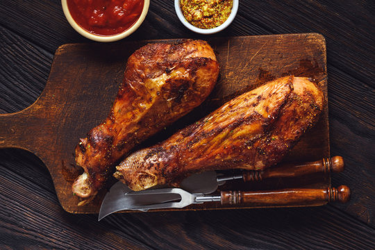 Roasted turkey legs, on dark wooden background.