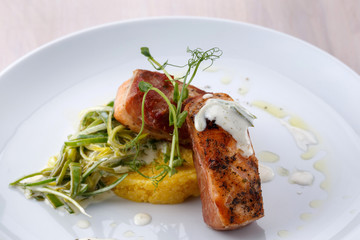 Salmon medallions wrapped in bacon on plate. Selective focus.
