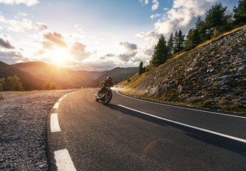 Motorcycle driver riding in Alpine road - obrazy, fototapety, plakaty