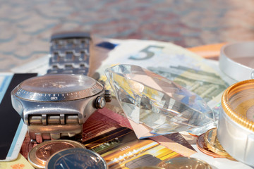 Signs of wealth: Euro banknotes, coins, credit card, jewelry, diamonds