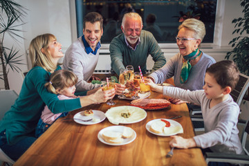 Multi generation family enjoying meal around table at home