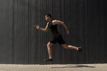 A side view shot of a fit young, athletic man jumping and running.