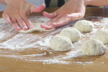 Woman's hands make yeast dough buns on the kitchen table.