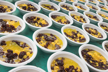 Thai dessert mix with clear jelly, red bean, dried monkey apple and another sweet thing put together in syrup in bowls in pattern