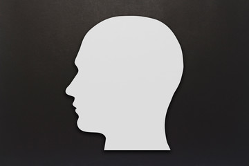 White cardboard head on a black background. Copy space. Flat lay, top view.