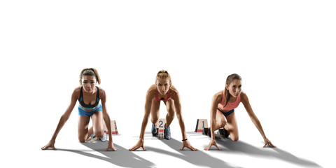 Obraz premium Female athletes on white background. Three Isolated women in sport clothes on starting line prepares to run 