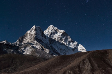 Ama Dablam mountain peak lit up by a bright moonlight on a starry night. Bewitching photo.