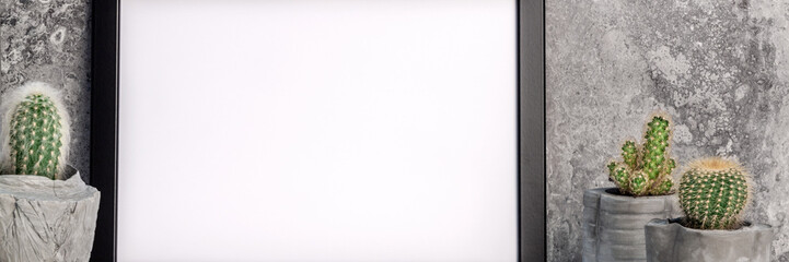 Black empty mockup frame on the background of a stone wall. Cactuses in concrete..  diy pots. White smooth shelf. Panoramic real photo