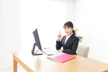 スーツ姿で指をさす若い女性