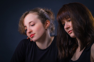 Two girls are carefully looking somewhere, probably their eyes are directed to the laptop screen