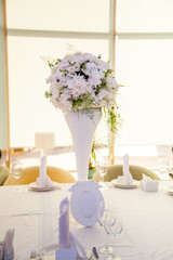 Wedding decor. Bouquet of white flowers on gold background in restaurant
