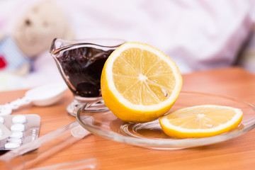 Lemon, jam and pills on the table on the background of a children's bed with a soft toy