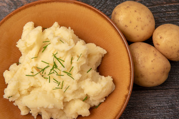 Close up image of a bowl of mashed potato with whole potatoes 