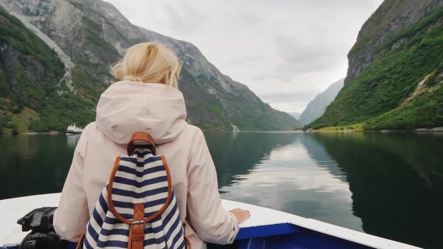 A fascinating journey through the fjords of Norway. Woman stands on the prow of a cruise ship
