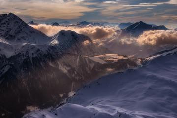 Fantastic dreamy sunrise on top of rocky mountain with view into misty valley. Foggy mountain. Sunset clouds. Misty peaks. Foggy landscape. Top of High mountains, covered by snow.