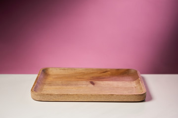 wooden cutting board on white table on pink background