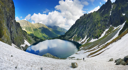 Morskie Oko. High Tatras, Poland, May 27, 2018. Beautiful landscape of snowy mountain tops and the lake between them. - obrazy, fototapety, plakaty