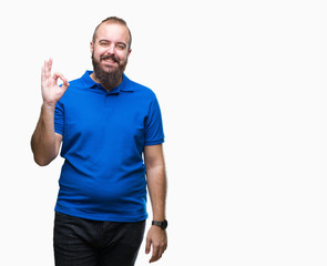 Young caucasian hipster man wearing blue shirt over isolated background smiling positive doing ok sign with hand and fingers. Successful expression.