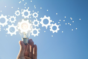 Hand holding light bulb and gears mechanism. Concept of Idea, Imagination, Creativity
