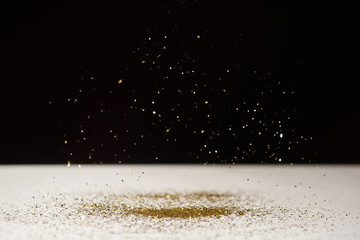 selective focus of white table with bright sparkles isolated on black