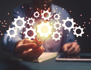 Man holding light bulb and gears mechanism. Concept of Idea, Imagination, Creativity