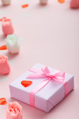 background of gifts with confetti hearts and roses, boxes wrapped in decorative paper on pastel colored pink background, holiday concept and love