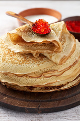Stack of russian thin pancakes blini with red caviar and fresh sour cream